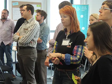 Arbeitsgruppe betrachtet Ergebnisse  stehend im Raum im Visions-Workshop