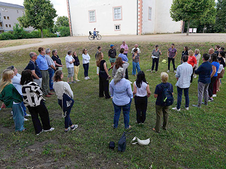 beim Workshop zur Teamentwicklung stehen die Teilnehmenden bei einer Aufstellung im Kreis auf einer Wiese 