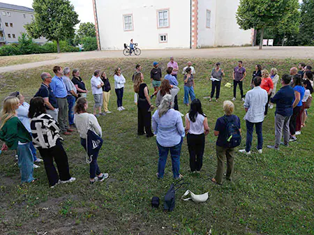 Menschen stehen im Kreis auf einer grünen Wiese bei einer Aufstellung imm Workshop zur Teamentwicklung
