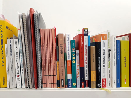 Bücher mit Methoden, Spielen und Moderationsprozessen in einer Reihe uf einem Schrank