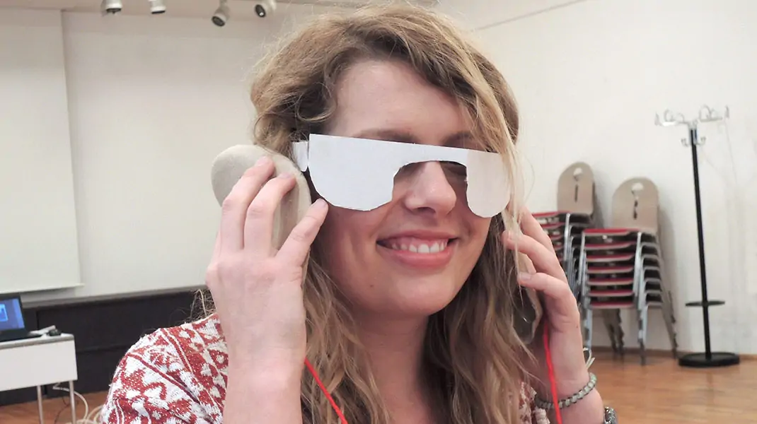 im Design Thinking-Training: Frau mit Brille aus Pappe und Papp Hörgeräten