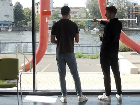 zwei Teilnehmer stehen im Strategie Workshop vor einer Zeitleiste am Fenster 
